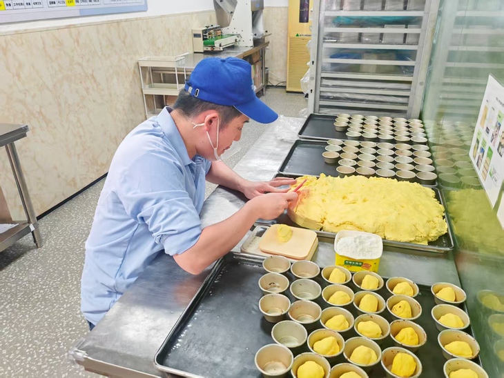 这家“星星”烘焙店保证:除了爱 零添加 孤独症员工戴着口罩,用干净的双手正在认真制作蛋挞皮。人民网记者 王子锋摄