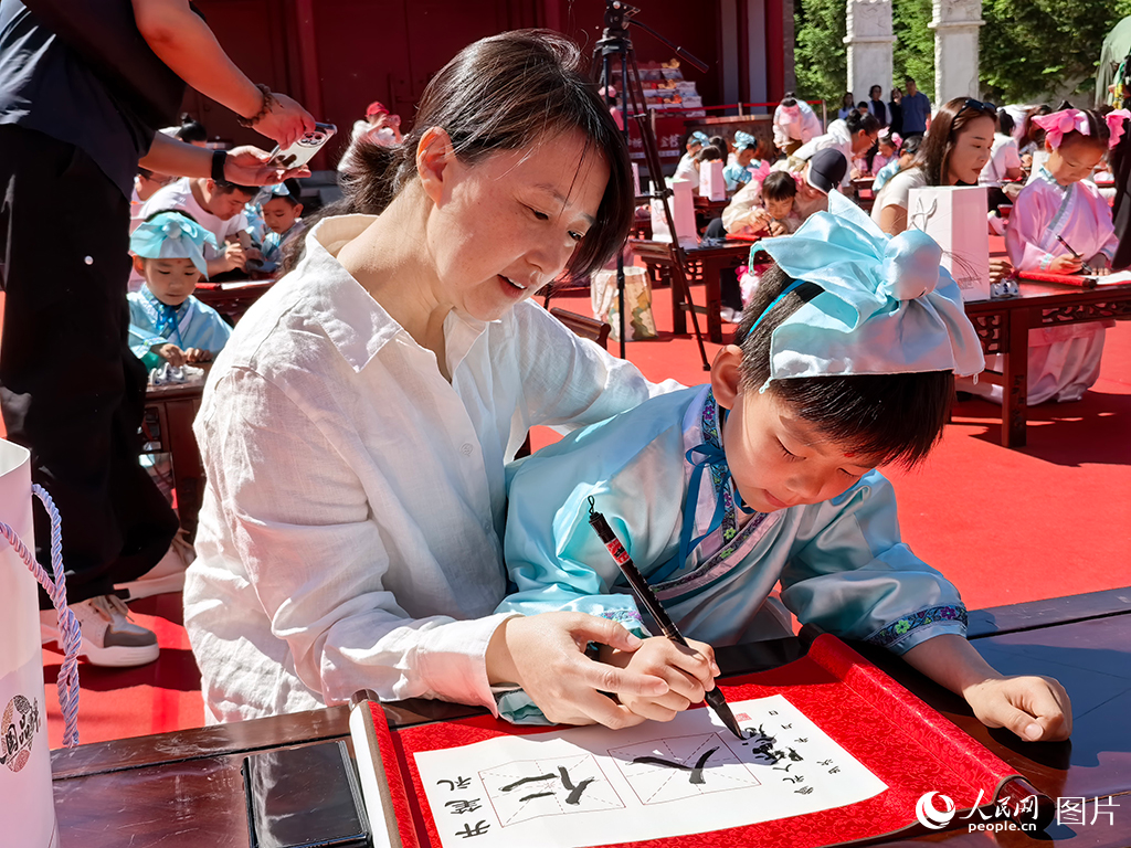 2026年5月30日，在吉林长春文庙博物馆传统启蒙礼活动现场，孩子们提笔书写“仁”与“人”，在古韵雅乐中笃学明礼，开启崭新的成长篇章。人民网记者 王帝元摄